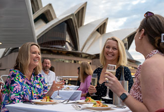 Guests enjoy lunch against the stunning backdrop of the Harbour Bridge aboard the Magistic cruise lunch
